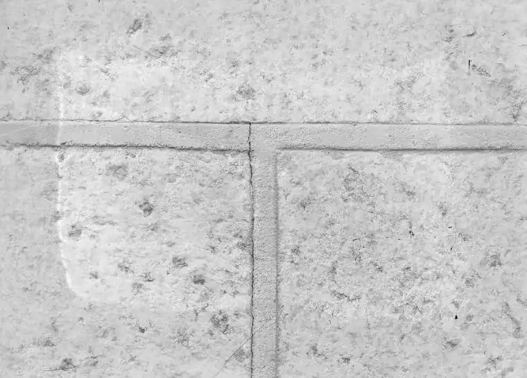 Black and white close-up of a thin crack running along the mortar joints between large masonry blocks